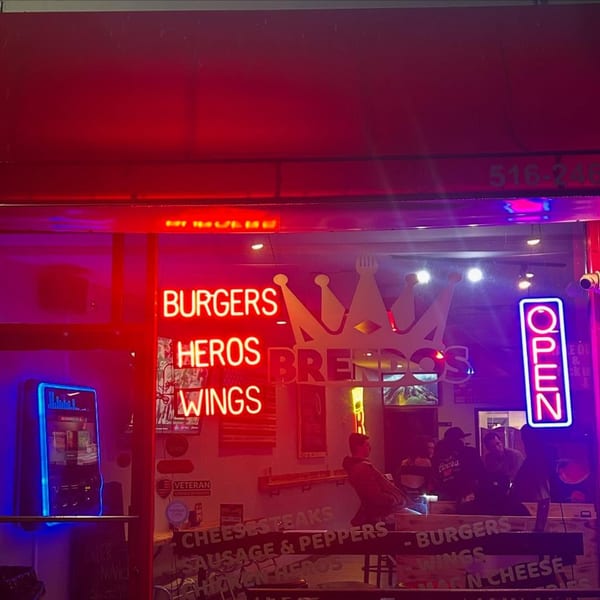 Brendos restaurant exterior at night, with neon signs for "Burgers, Heros, Wings" and an "Open" sign.