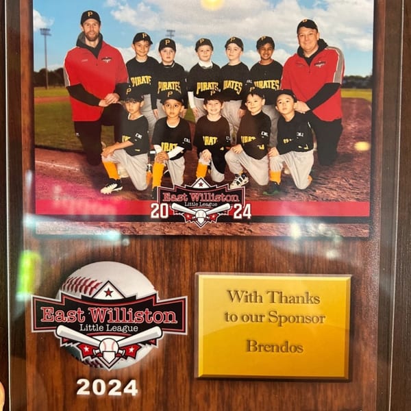 A plaque with a baseball team photo, featuring young players and coaches, sponsored by Brendos.